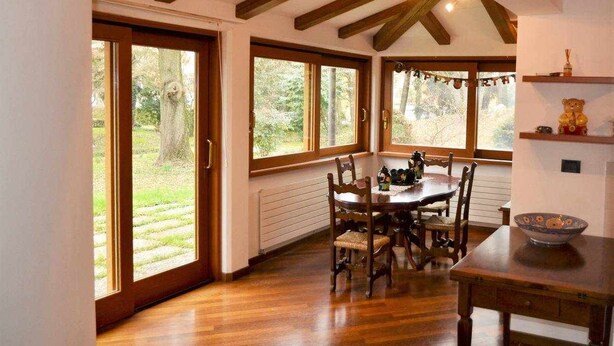 A dining area with a wooden table and chairs, large windows, and a view of the outdoors. - Padua Villa with large private park (Campodarsego)
