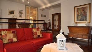 A living room with a red sofa, a white table with a lantern, and a wooden cabinet. - Padua Villa with large private park (Campodarsego)