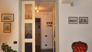 A spacious living room with a red armchair, a large potted plant, and a patterned rug. - Padua Villa with large private park (Campodarsego)