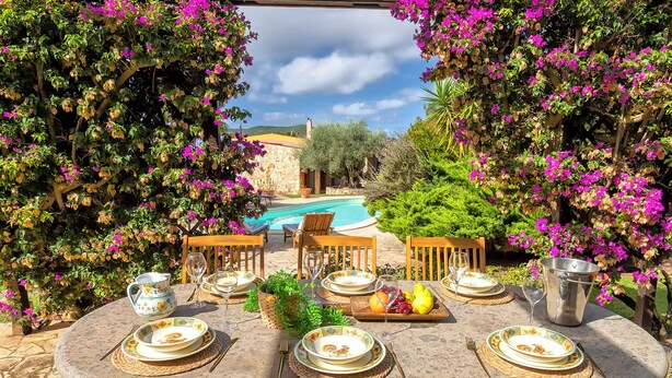 Un espace de restauration en plein air avec vue sur la piscine, entouré de plantes en fleurs.