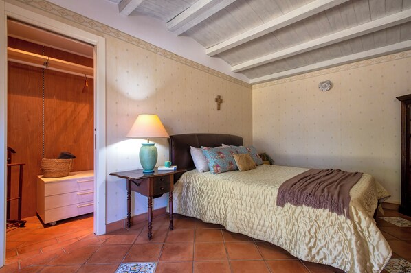 A bedroom with a bed, a nightstand, a lamp, and a wardrobe.
