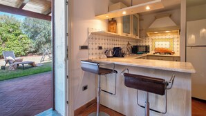 Une cuisine moderne dotée d’un coin bar, d’un four encastré et offrant une vue sur le jardin.