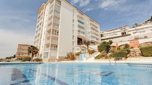 Ett modernt hotell med en swimmingpool, flera balkonger och ett vackert anlagt trädgårdsområde.