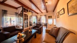 A cozy living room with a wooden ceiling, a dining area with a table and chairs, and a sofa.