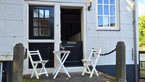 A building with a black door and windows, a small table with chairs, and a sign reading "BISTRO DE PROVENCE".