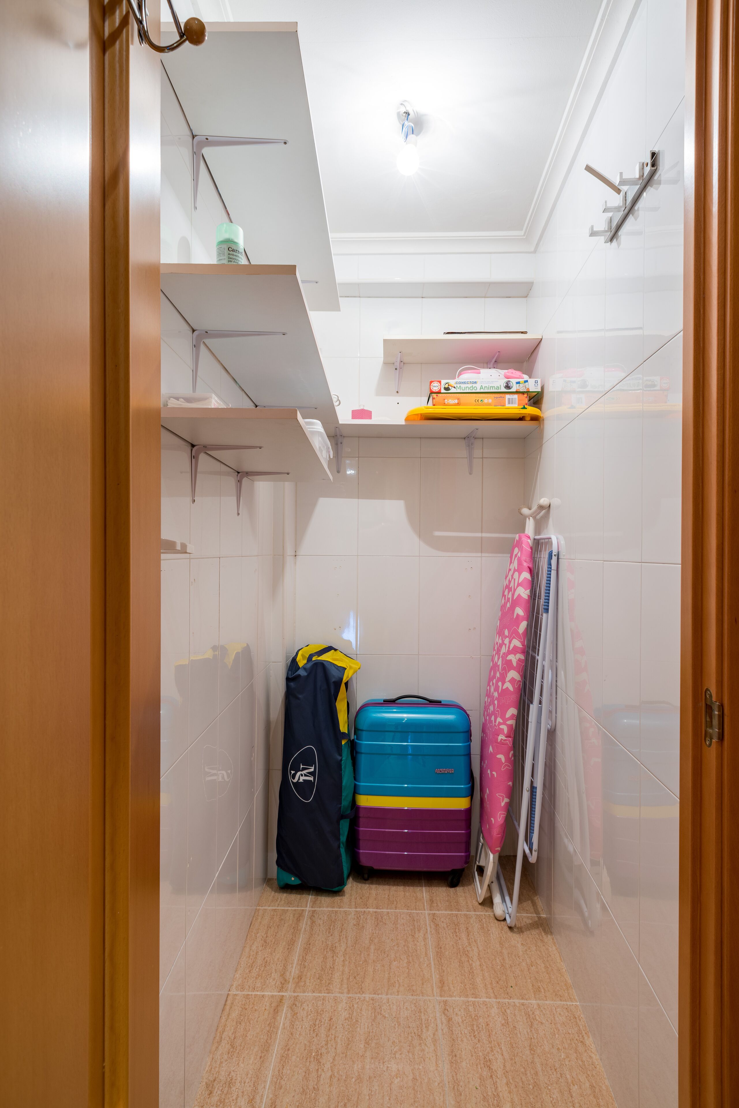 A small bathroom with a shower, a towel rack, and a shelf with toiletries.