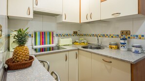 A kitchen with white cabinets, a granite countertop, a toaster, a sink, and a pineapple in a basket.