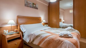 A neatly made bed with a striped bedspread, a bedside table with a lamp, and a mirror on the wall.
