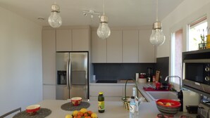 Eine moderne Küche mit Edelstahlgeräten, einer zentralen Kochinsel mit Obst und Pendelleuchten.