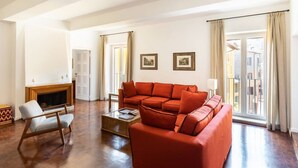 A spacious living room with a large red sofa, a wooden chair, and a fireplace. - Residenza Torre Vecchiarelli - apt 4 (Roma)