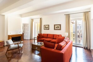 A spacious living room with a large red sofa, a wooden chair, and a fireplace. - Residenza Torre Vecchiarelli - apt 4 (Roma)