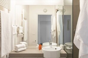 A modern bathroom with two sinks, a large mirror, and a towel rack with folded towels. - Residenza Torre Vecchiarelli - apt 4 (Roma)