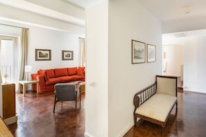 A spacious living room with a red sofa, a wooden bench, and framed pictures on the wall. - Residenza Torre Vecchiarelli - apt 4 (Roma)