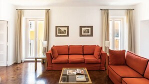 A living room with a red sofa, a glass coffee table, and two framed pictures on the wall.