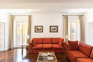 A living room with a red sofa, a glass coffee table, and two framed pictures on the wall. - Residenza Torre Vecchiarelli - apt 4 (Roma)