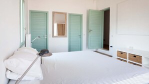 A bedroom with a bed, a nightstand, a lamp, two green doors, and a mirror on the wall. - Traditional Stone Villa with Sea Views, Private Pool and 10 mins from beach (Karefiliana)