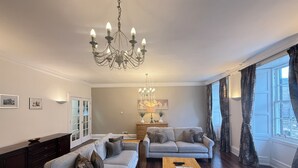 Un soggiorno con un lampadario, due divani, un tavolino da caffè e una lampada.