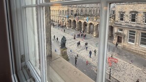 Vista dalla finestra su una piazza storica con edifici in pietra e una statua.