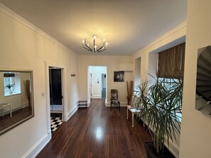 A spacious hallway with hardwood floors, a chandelier, a large mirror, and a potted plant. - Edinburgh Royal Mile - Parliament Square Apartment (Edinburgh)