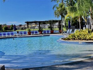 A swimming pool with lounge chairs and palm trees.