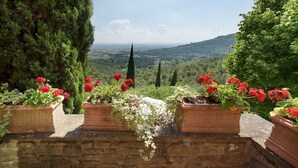Eine Steinmauer mit Blumenkästen und Blick auf eine hügelige Landschaft.
