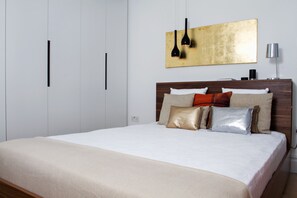 Une chambre moderne avec un grand lit, une tête de lit en bois et un design minimaliste.