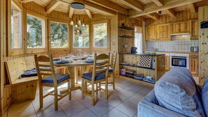 Interior de una cabaña de madera con comedor, cocina y zona de estar.