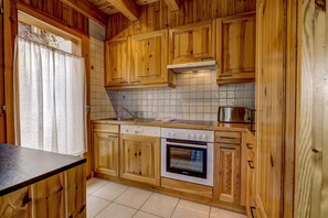 A kitchen with wooden cabinets, a dishwasher, an oven, and a microwave. - Chalet Colonia - La Tzoumaz, 4 Vallees (La Tzoumaz)