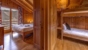 Una cabaña de madera con un ventanal grande, una litera y un escritorio de madera.