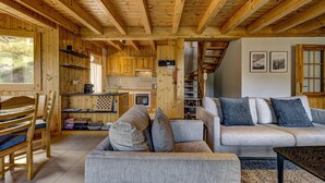 Un interior de madera con un sofá, sillas y una zona de cocina.
