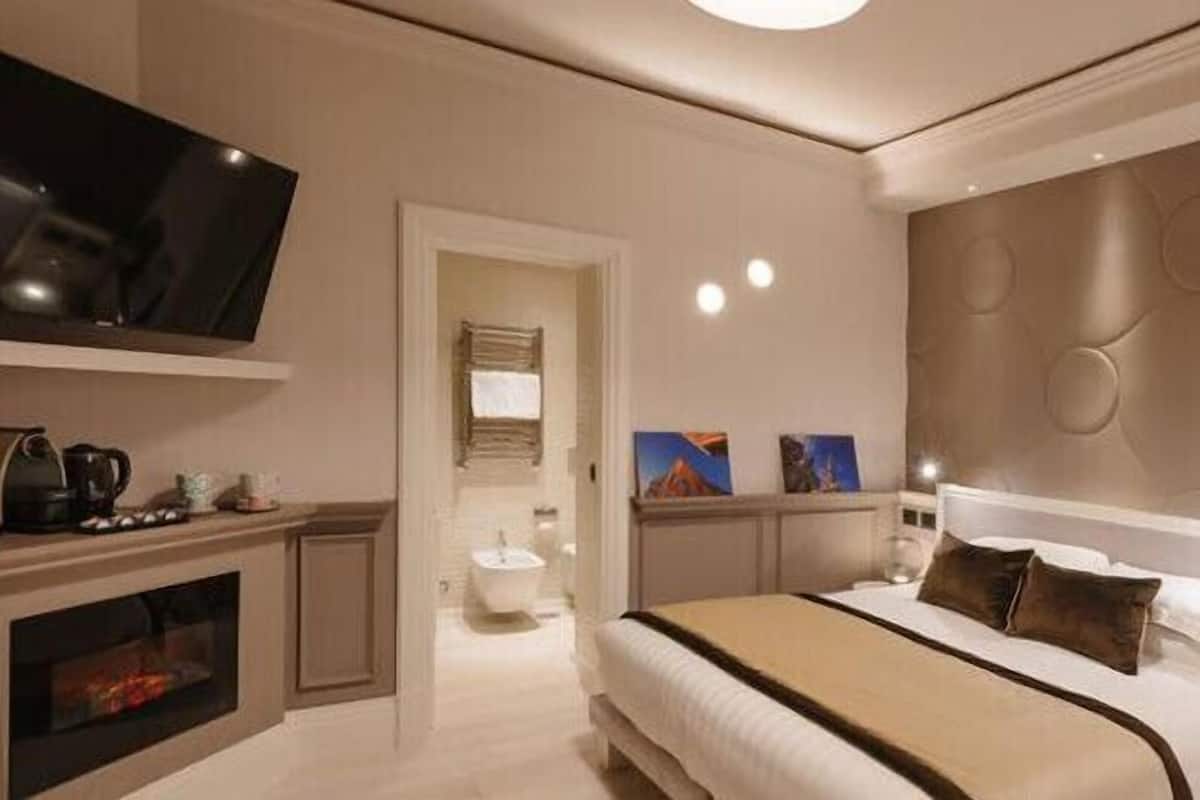 Une chambre d’hôtel moderne dotée d’un grand lit, d’une télévision à écran plat, d’une cheminée et d’un mur décoratif.