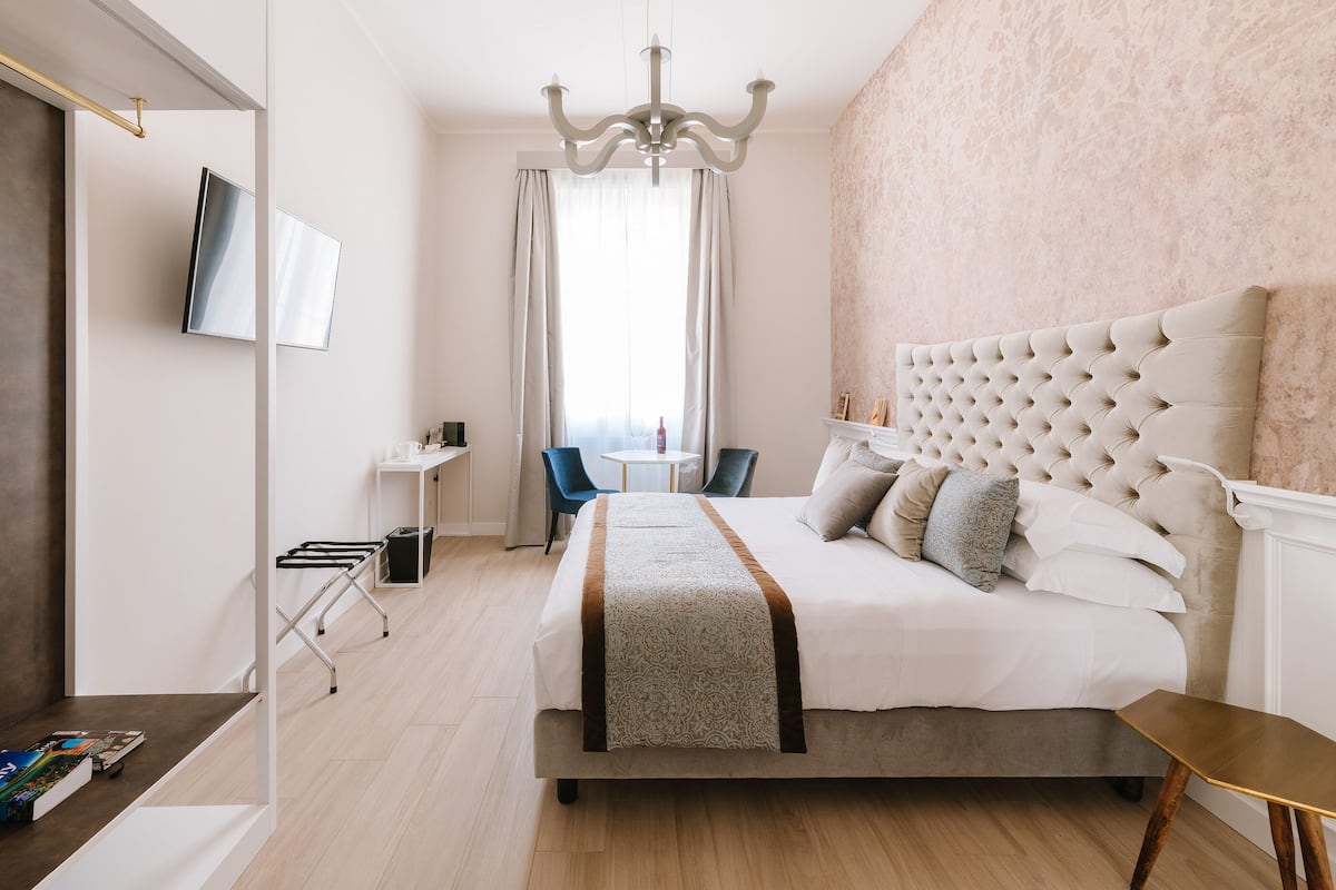 Une chambre d’hôtel moderne avec un grand lit, un téléviseur fixé au mur, une petite table et une chaise.