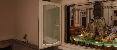 A room with a window overlooking a detailed fountain sculpture.