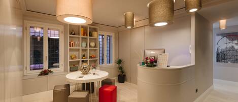 A modern interior with a round table, beige walls, and a red accent chair.