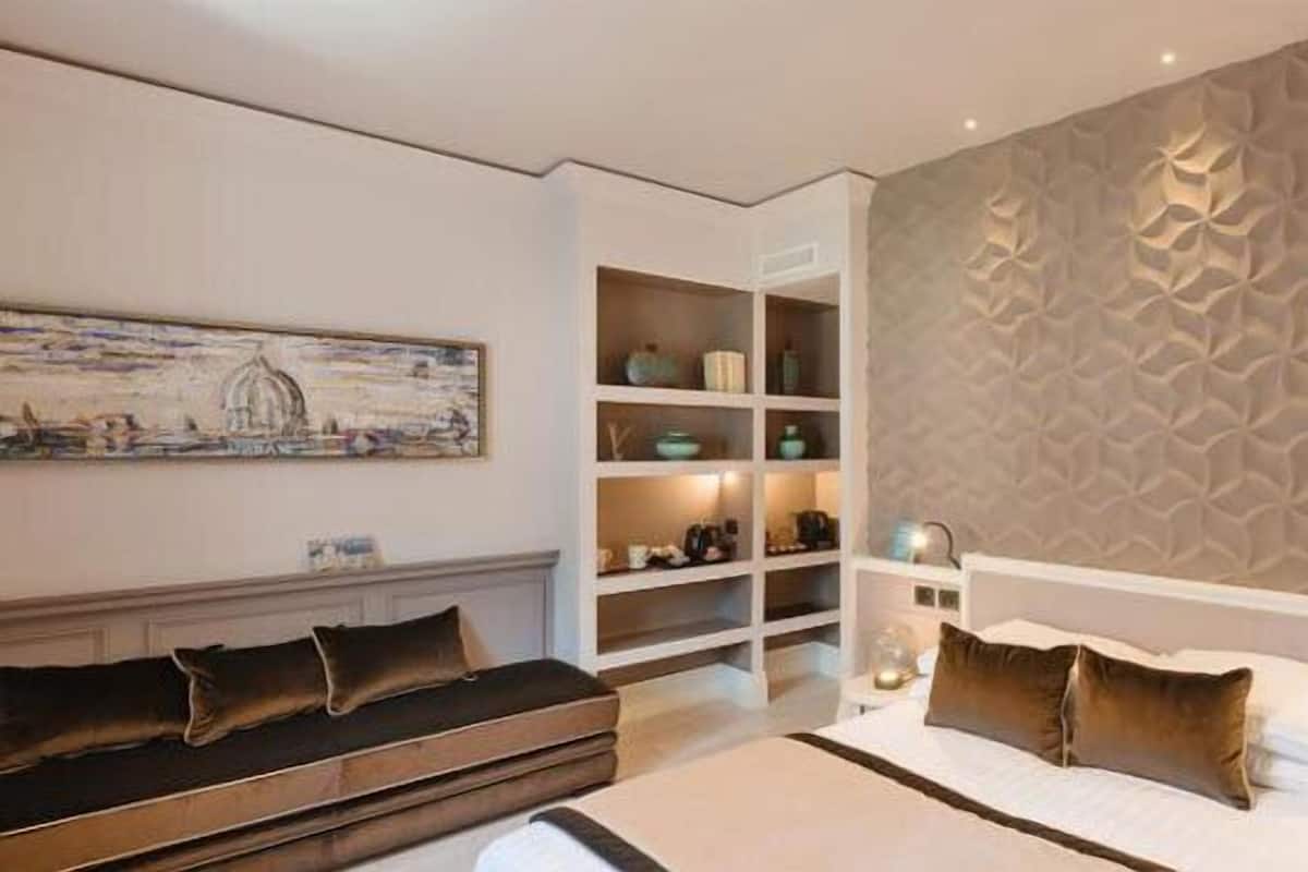 Une chambre à coucher moderne avec un lit, un banc, une bibliothèque intégrée et un mur à texture.