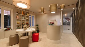 Una cucina moderna con un tavolo da pranzo rotondo, due sgabelli, un pouf rosso e un'isola beige con piano di lavoro.