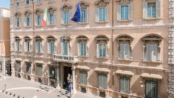 Un edificio histórico con numerosas ventanas y banderas, incluyendo la bandera italiana.