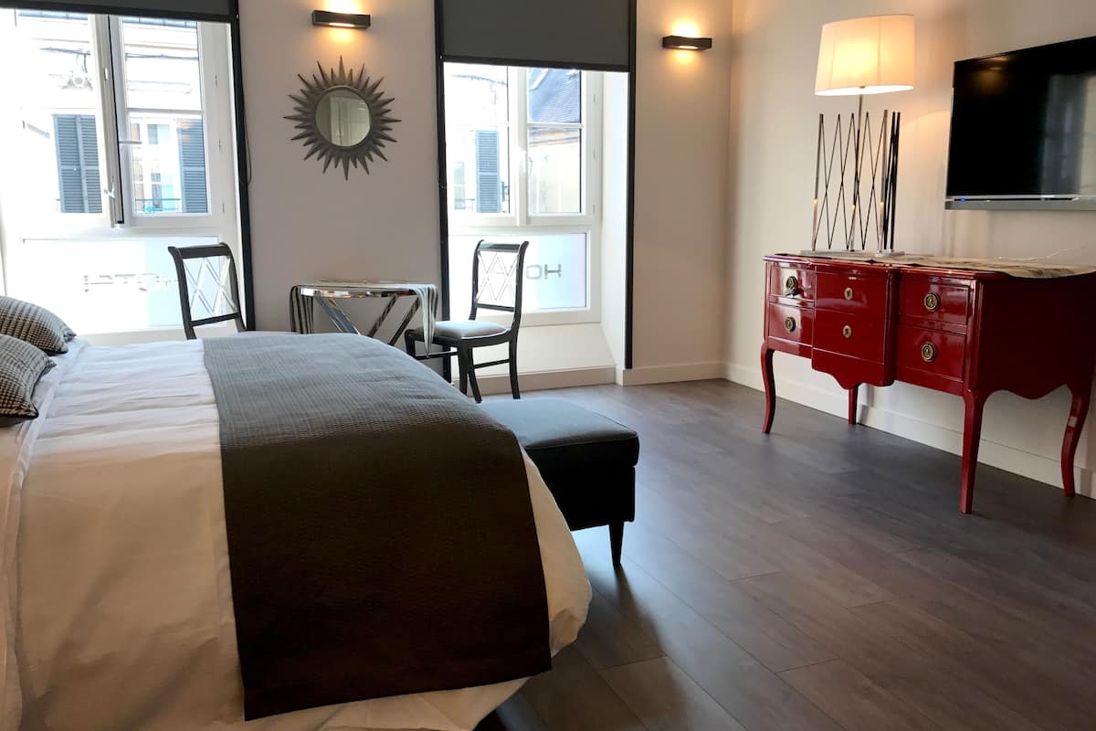 Une chambre à coucher avec un grand lit, un bureau, une chaise, une commode et un téléviseur.