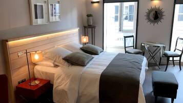 A modern hotel room with a large bed, bedside lamps, a small table with a chair, and a view of the outside.