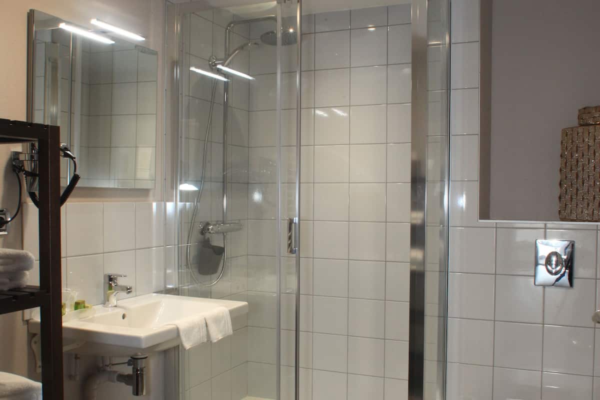 Une salle de bain moderne avec une douche à parois de verre, un lavabo blanc et des toilettes.