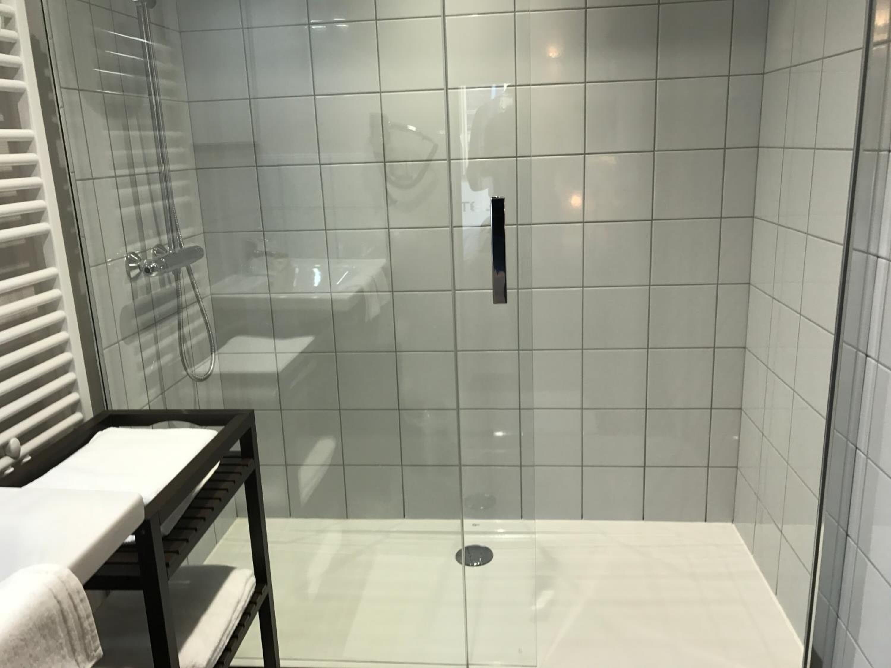 A modern bathroom with a glass-enclosed shower, a white sink, and a towel rack.