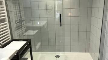 A modern bathroom with a glass-enclosed shower, a white sink, and a towel rack.