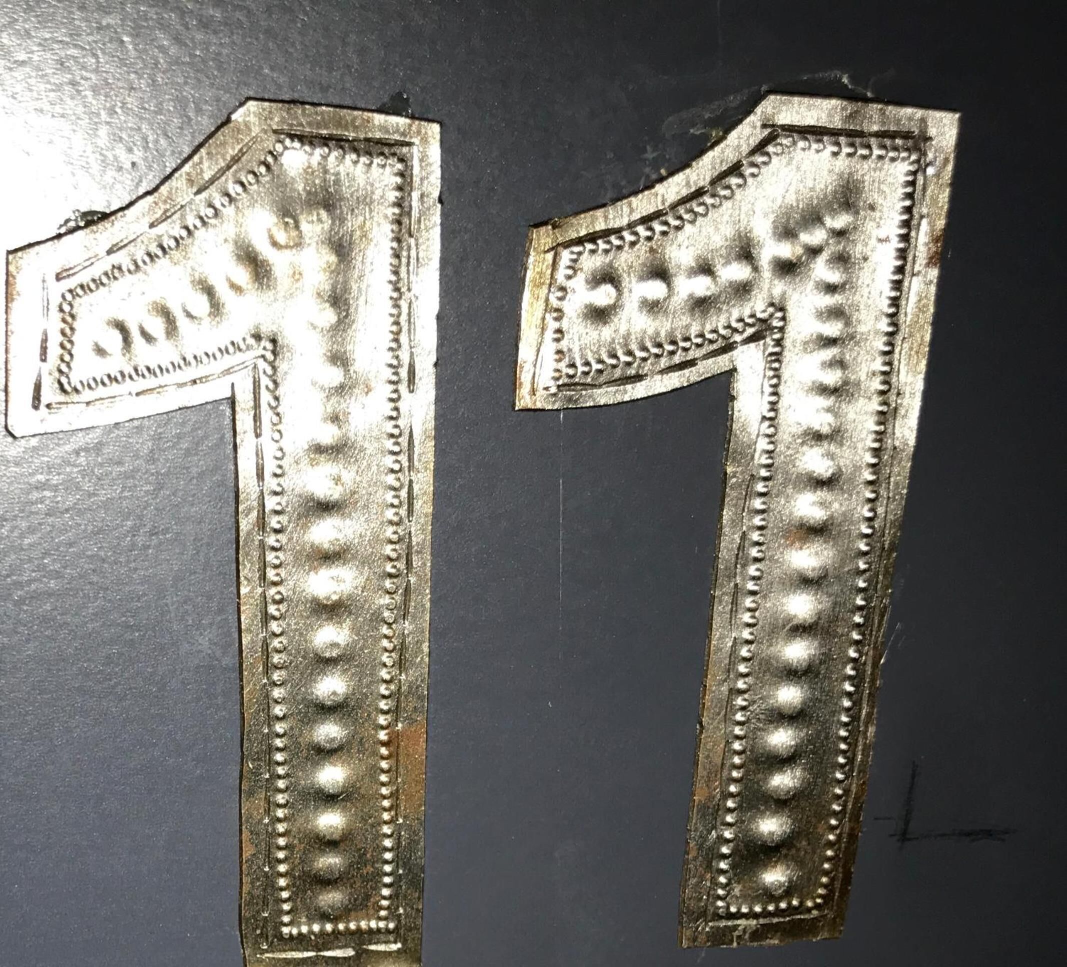 Dos números metálicos '1' con detalles en relieve, probablemente parte de una estructura o decoración más grande.