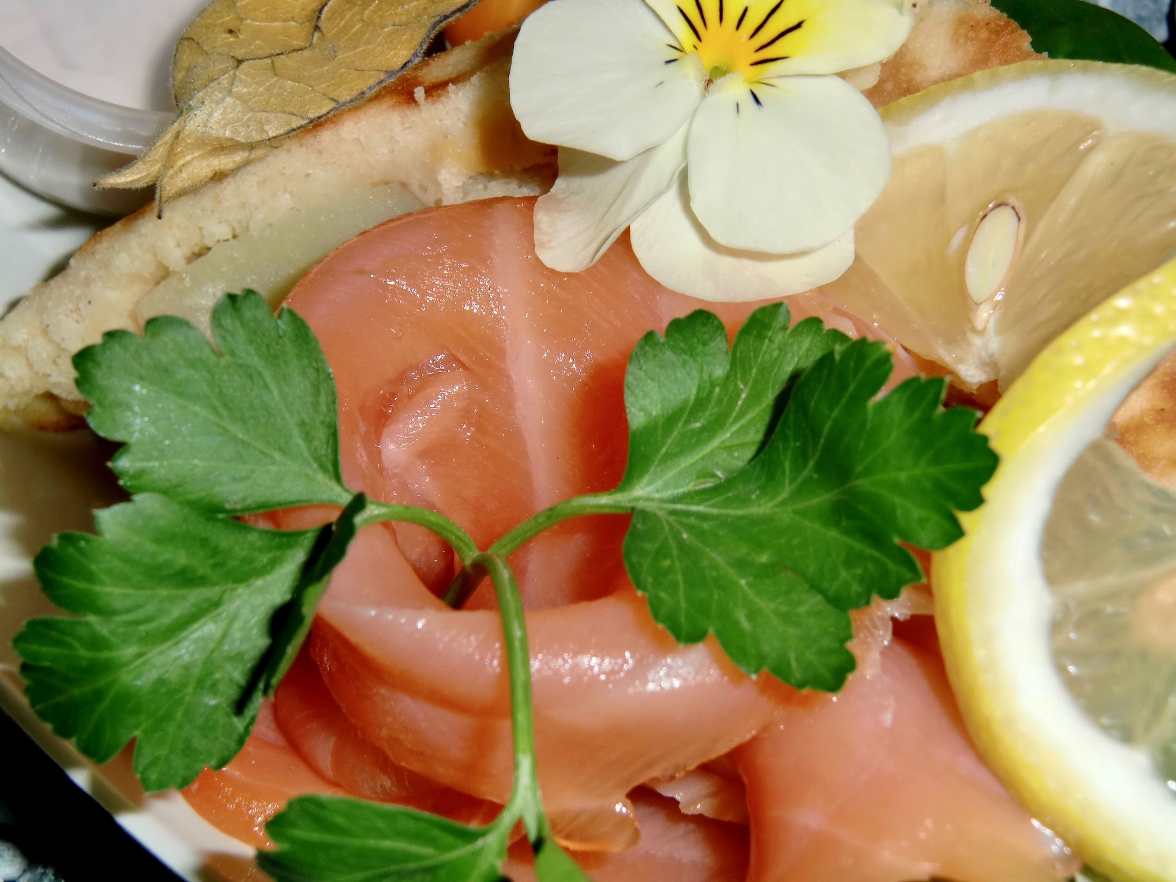 Un piatto di cibo con salmone affumicato, prezzemolo e fette di limone.