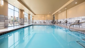 An indoor swimming pool with clear blue water, surrounded by chairs and tables, large windows, and a tiled wall. - Hampton Inn Salt Lake City Cottonwood UT (Salt Lake City)