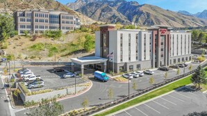 A hotel with a modern design, located in a mountainous area with a parking lot and a road leading to it. - Hampton Inn Salt Lake City Cottonwood UT (Salt Lake City)