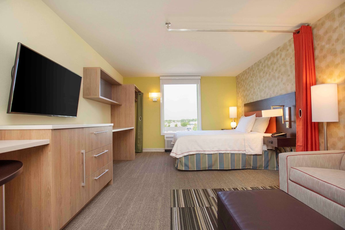 Una habitación de hotel con cama, escritorio, televisor y ventana.