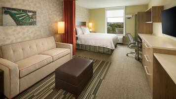A hotel room with a bed, a sofa, a desk, a TV, and a window with a view.