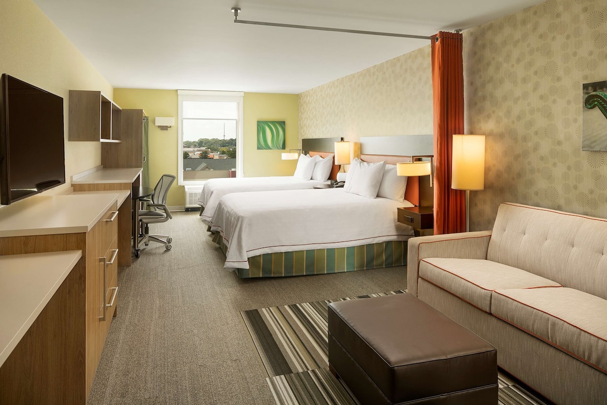 Habitación de hotel con dos camas, un sofá, un escritorio y un televisor.