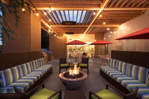 An outdoor patio with a fire pit, seating areas, and string lights. - Home2 Suites by Hilton Mishawaka South Bend, IN (Mishawaka)